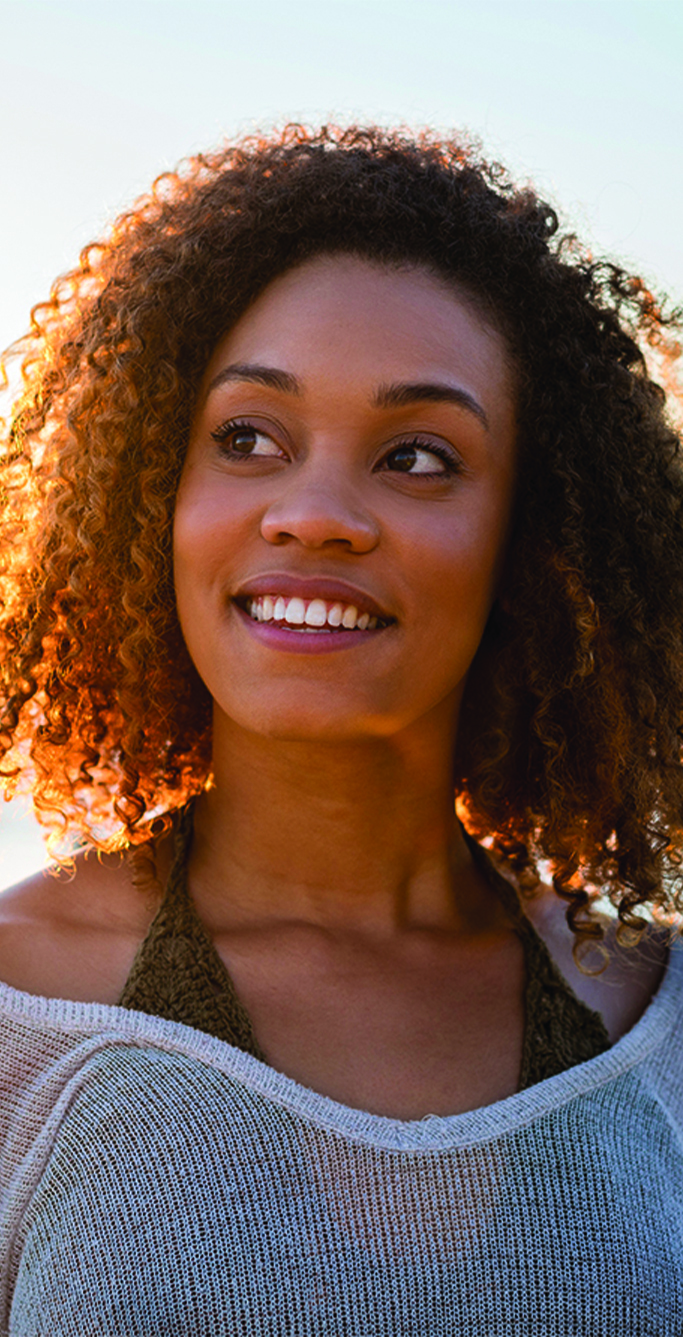 Woman smiling, looking off into the distance.